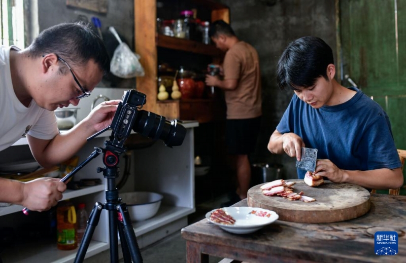 陳家寨村で、臘肉（燻製豚肉）を宣伝するショート動畫を撮影する「念郷人周周」撮影チームのメンバー（9月26日撮影?楊文斌）。